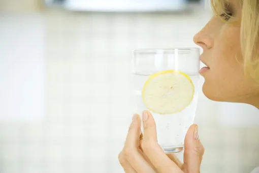 Девушка пьет воду с лимоном