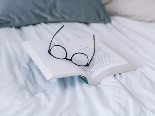 Книга и очки на кровати
