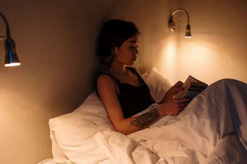 Девушка читает книгу в кровати