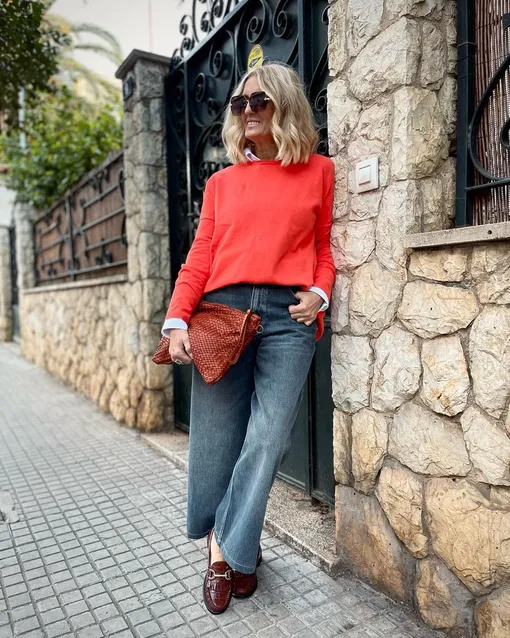 Чтобы составить стильный образ для женщины после 50 лет, можно сочетать яркий свитер и прямые джинсы